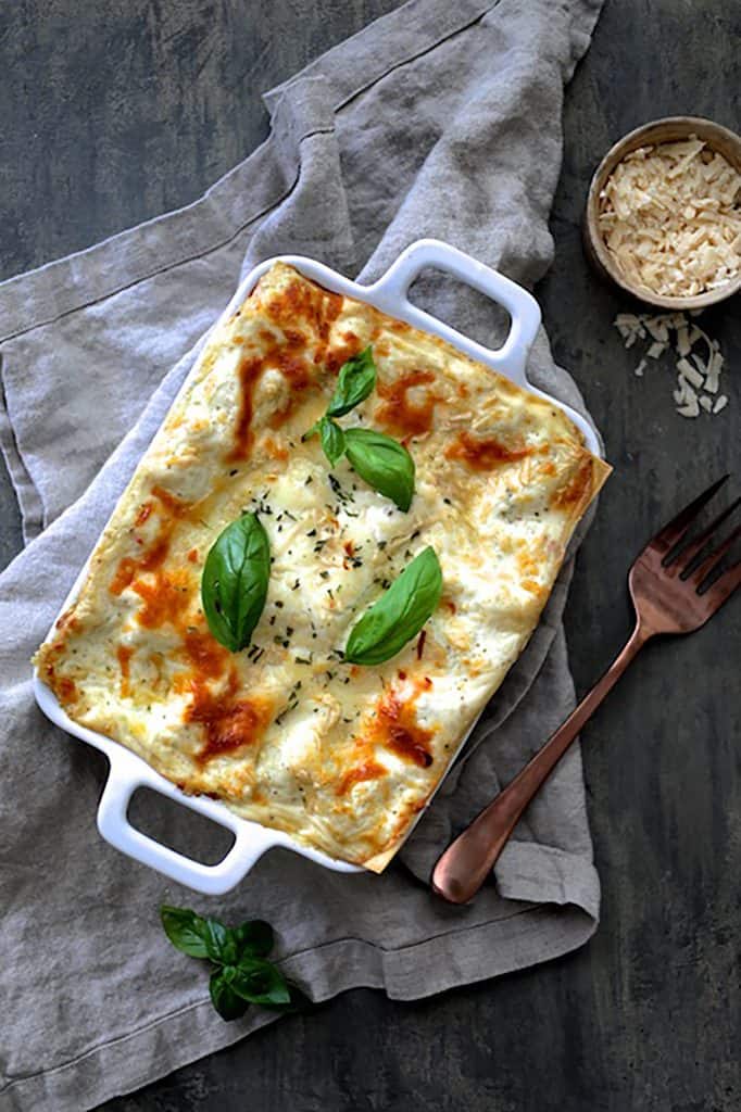 Photo of Lasagna with Pesto Green Beans and Potatoes on gray napkin garnished with fresh basil.