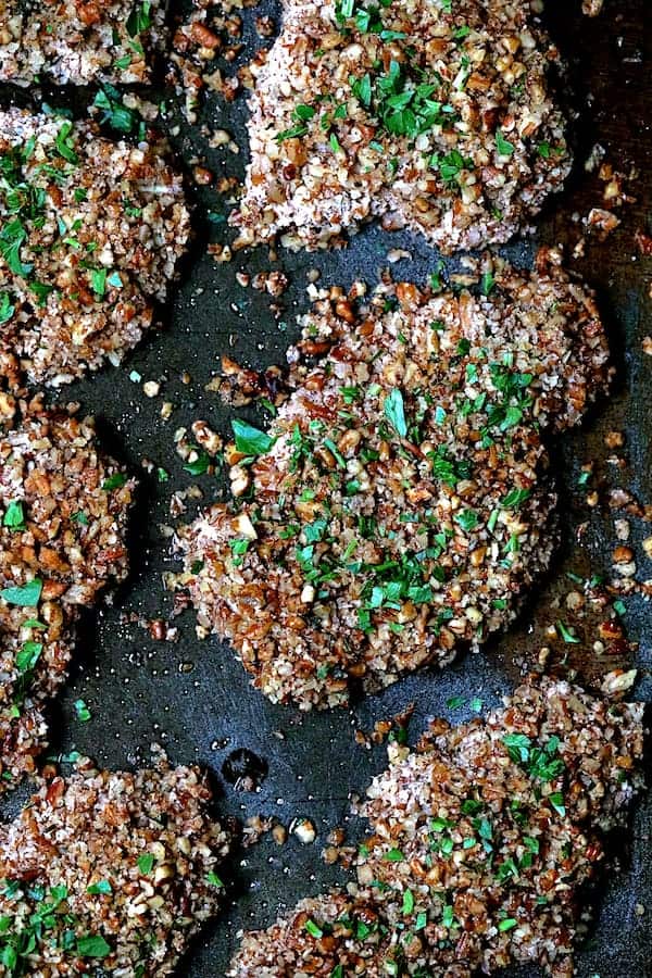 Close-up photo of Pecan Crusted Turkey Cutlets on baking sheet sprinkled with parsley.