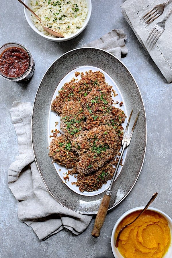 Photo of Pecan Crusted Turkey Cutlets with Red Onion Marmalade on gray-rimmed platter with meat fork.