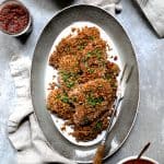 Pecan Crusted Turkey Cutlets with Red Onion Marmalade on oval gray-rimmed platter with meat fork.