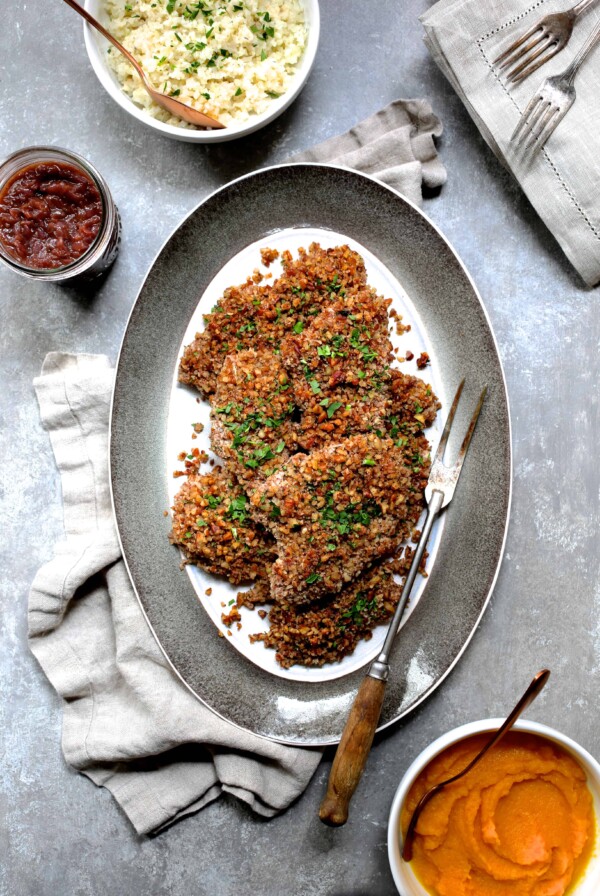 Pecan Crusted Turkey Cutlets with Red Onion Marmalade on oval gray-rimmed platter with meat fork.