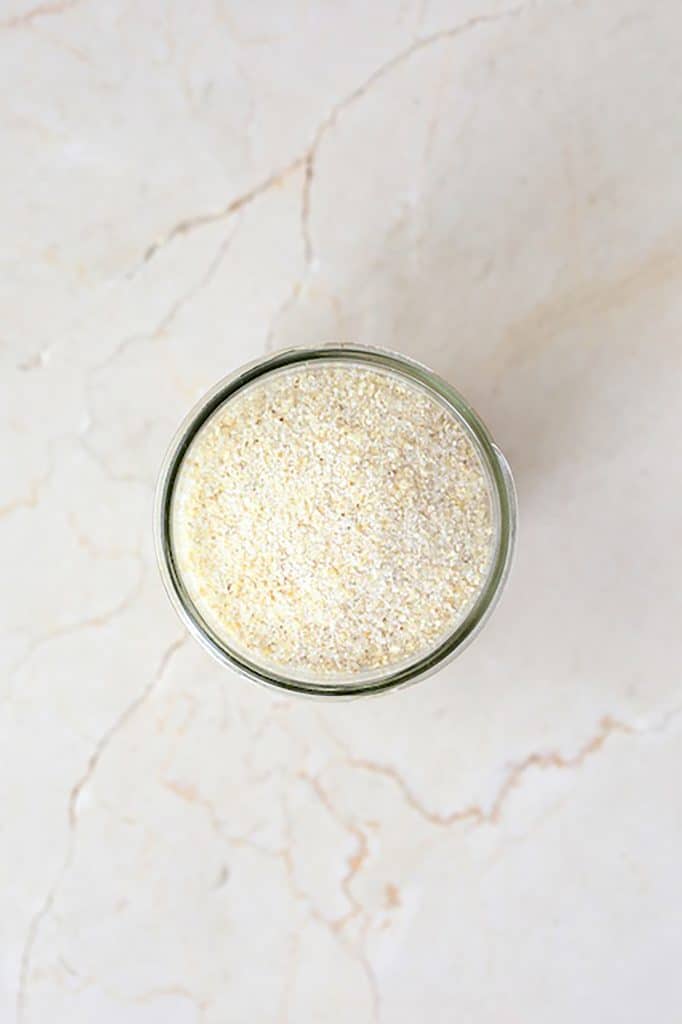 Photo of grits in glass jar on white marble surface.