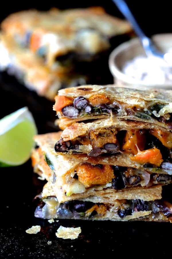 Close-up photo of stack of four pieces of Sheet Pan Quesadillas with Sweet Potatoes, Poblanos and Black Beans with Chipotle Sour Cream.