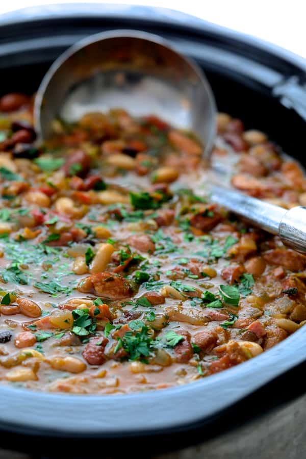 Photo of Slow Cooker Cajun 15 Bean Soup with Andouille Ham and Bacon in slow cooker with stainless steel ladle.