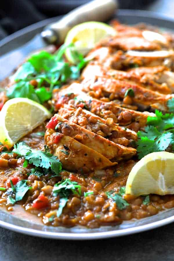 Close-up photo of Slow Cooker Moroccan Turkey and Lentils on gray-rimmed platter garnished with cilantro and lemon wedges.