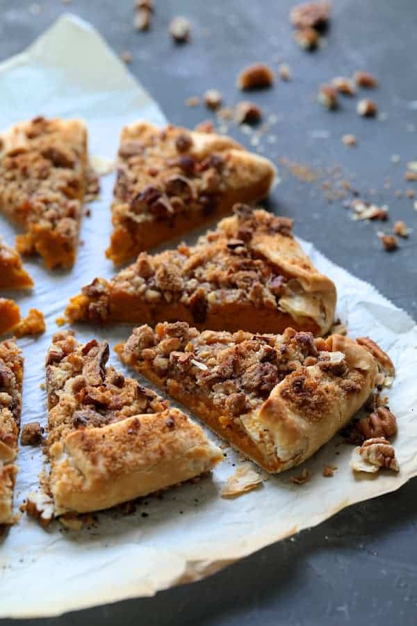 Photo of Sweet Potato Galette with Pecan Streusel Topping sliced into wedges on parchment paper.