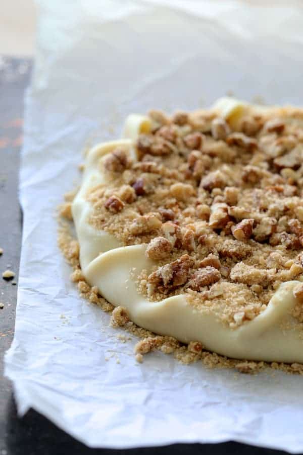 Process photo of galette with edges folded in topped with pecan streusel topping before being baked.