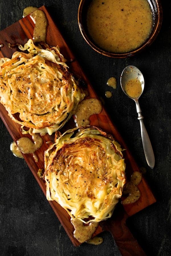 Photo of Roasted Cabbage Steaks with Mustard Vinaigrette on wood cutting board.