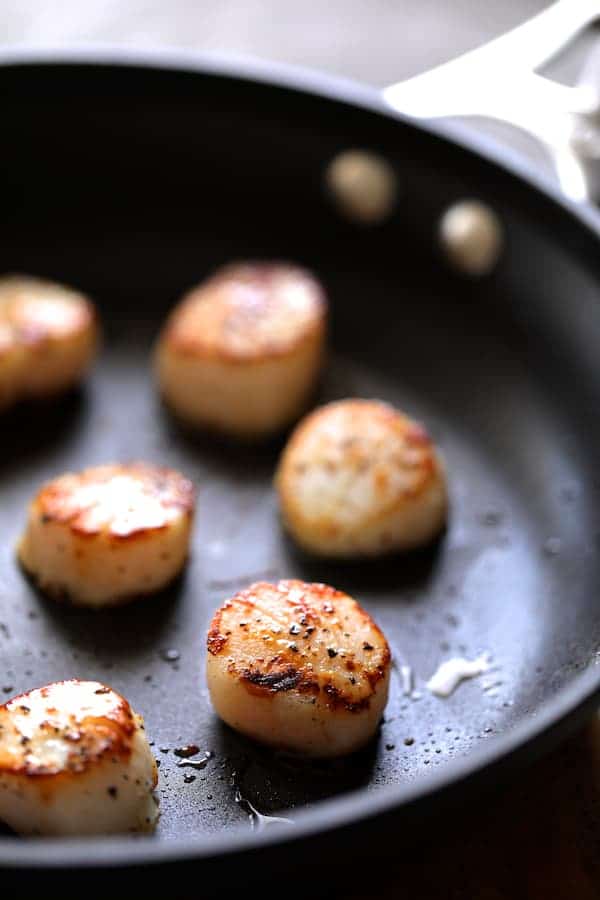 Photo of seared sea scallops in nonstick skillet.