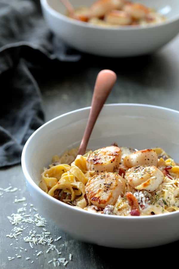 Photo of Seared Sea Scallops with Spicy Bacon Sun Dried Tomato Alfredo Sauce in white bowl.