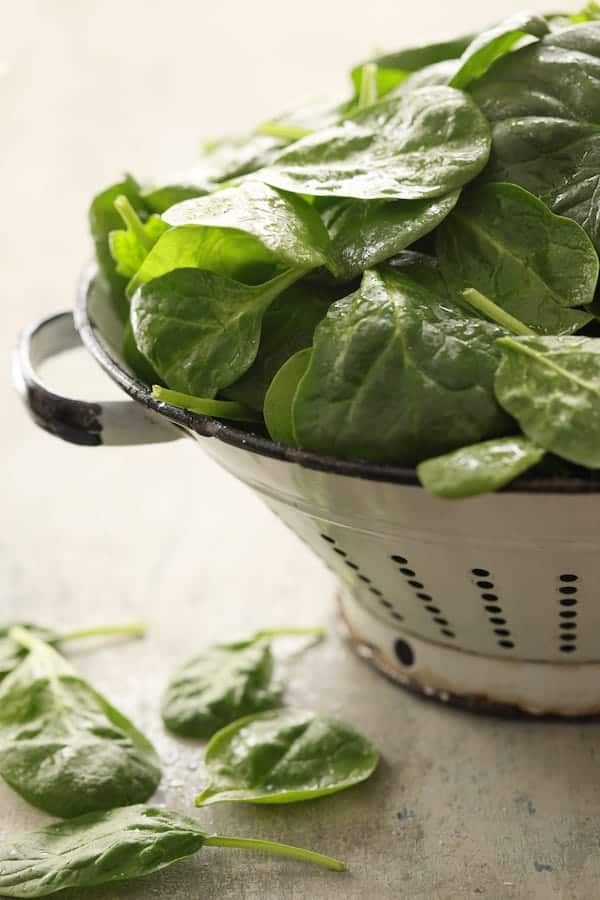 Photo of fresh spinach in white colander.
