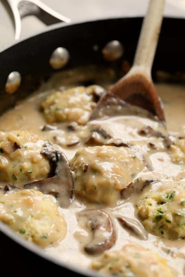 Photo of meatballs in the Marsala sauce being stirred with wooden spoon.