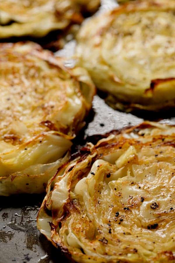 Close-up photo of roasted cabbage steaks on baking sheet.