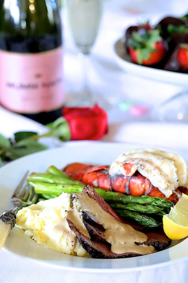 Photo of Steak au Poivre and Broiled Lobster Tail on white serving plate with asparagus.