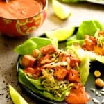 One Vegan Korean Tofu Lettuce Wrap with Tahini Gochujang Sauce and Spicy Slaw on black plate.