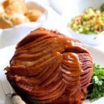 Slow Cooker Honey Ham on white platter with butcher knife nearby.
