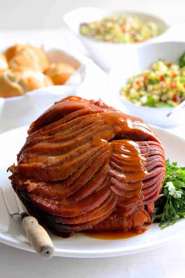Photo of Slow Cooker Honey Ham with Pineapple Salsa on white platter with sauce drizzled down the front.