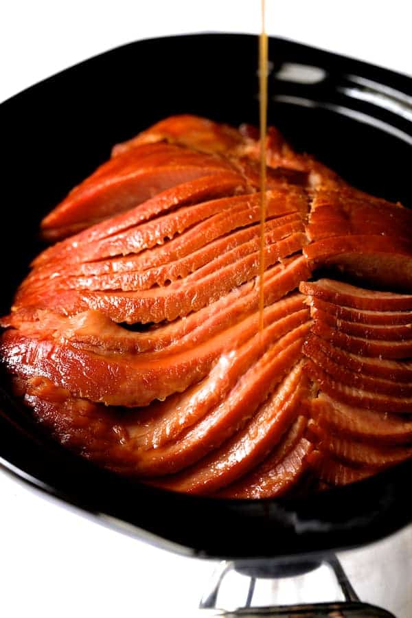 Photo of glaze being drizzled over spiral sliced ham in slow cooker.