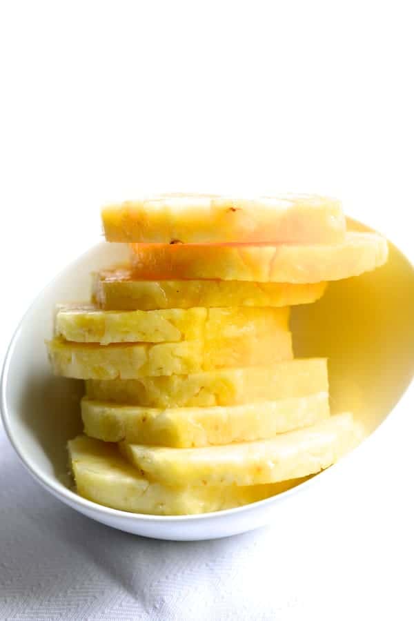 Photo of pineapple slices in white bowl.