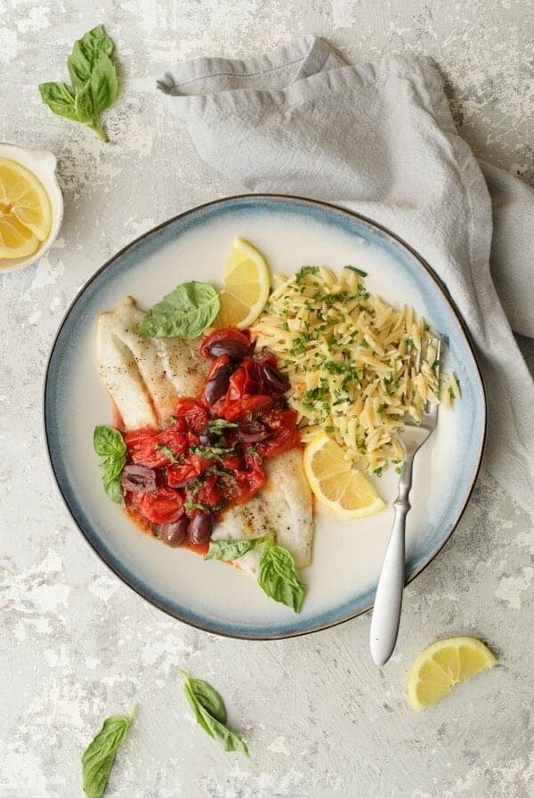 Baked Fish with Cherry Tomato Olive Sauce + Lemon Chive Asiago Orzo - Hero shot on light gray background with light gray napkin