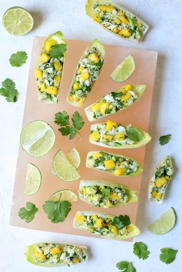 Crab Mango and Avocado Salad with Chile Lime Dressing in Endive - Overhead hero shot on pink salt block