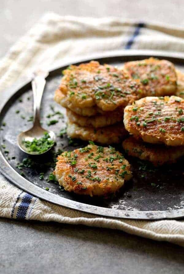 Parmesan Crusted Smashed Turnips - Stacked on metal tray and sprinkled with chives