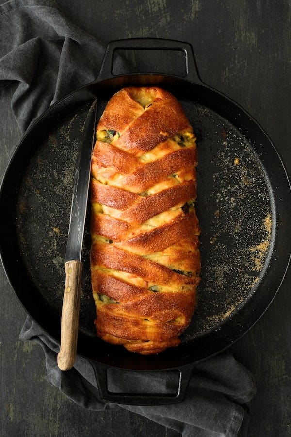 Photo of Savory Breakfast Strudel with Eggs, Sausage and Swiss Chard in cast iron pan with knife after being baked..