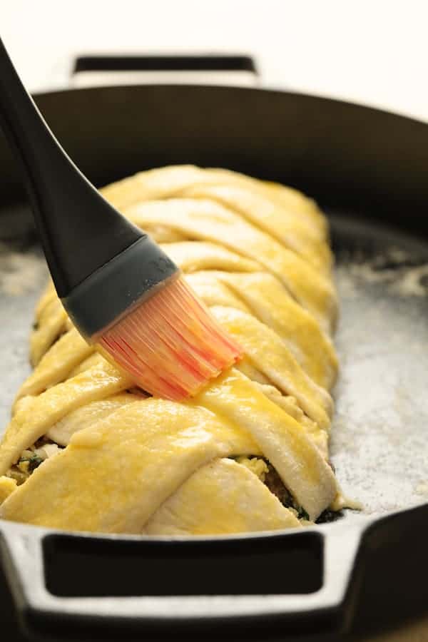 Photo of strudel with strips brought over the top and dough being brushed with egg wash.