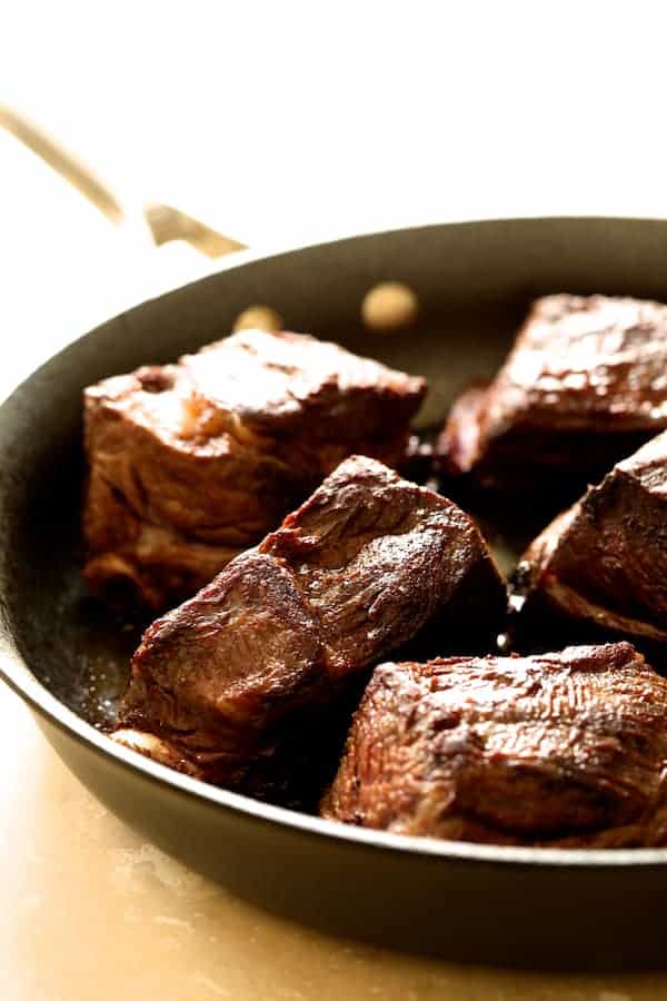 Photo of short ribs being browned in a skillet.
