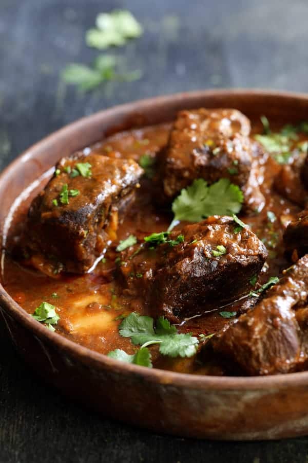 Close-up photo of Slow Cooker Beef Short Ribs Barbacoa with Cilantro Lime Cauliflower Rice in earthenware bowl garnished with cilantro.