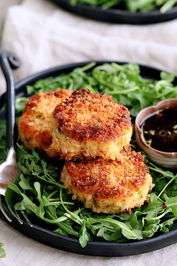 Photo of Tuna Kimchi Cakes with Soy Ginger Dipping Sauce on black plate with arugula and dipping sauce.