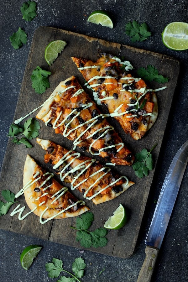 Photo of Chipotle Chicken Sweet Potato and Black Bean Flatbread Pizzas with Avocado Sour Cream on wood cutting board.