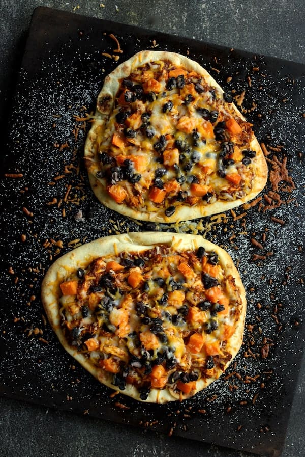 Photo of Chipotle Chicken Sweet Potato and Black Bean Flatbread Pizzas with Avocado Sour Cream on baking stone.