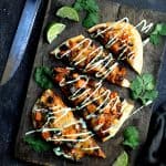 One Chipotle Chicken Sweet Potato and Black Bean Flatbread Pizzas with Avocado Sour Cream on wood cutting board.