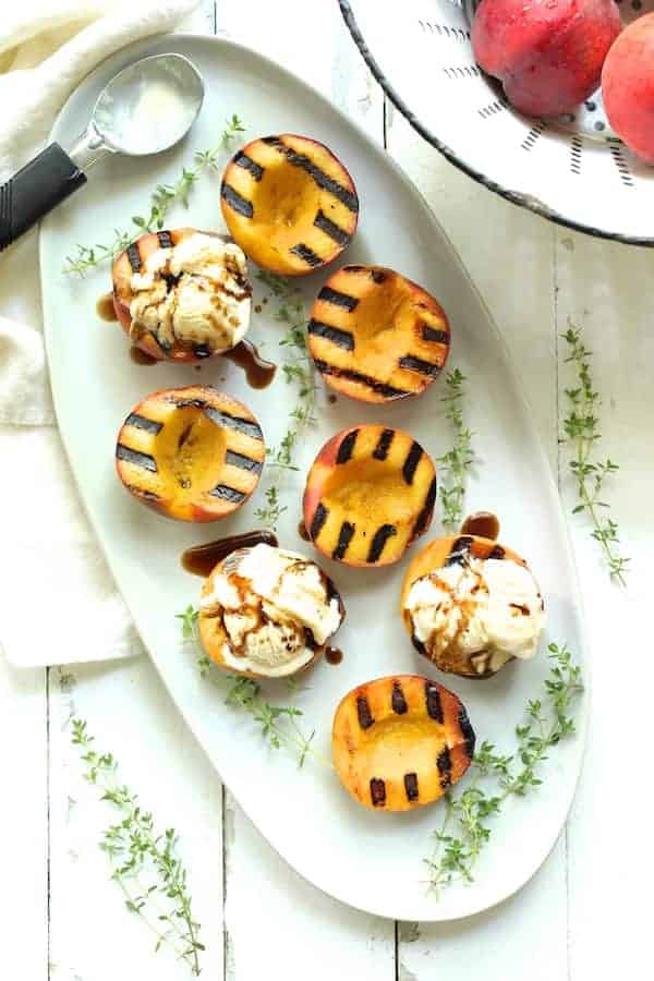 Photo of Grilled Peaches with Vanilla Ice Cream and Honey Balsamic Drizzle garnished with fresh thyme.