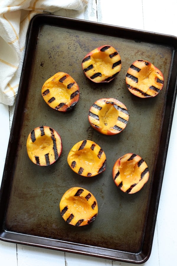 Photo of eight grilled peaches on sheet pan.