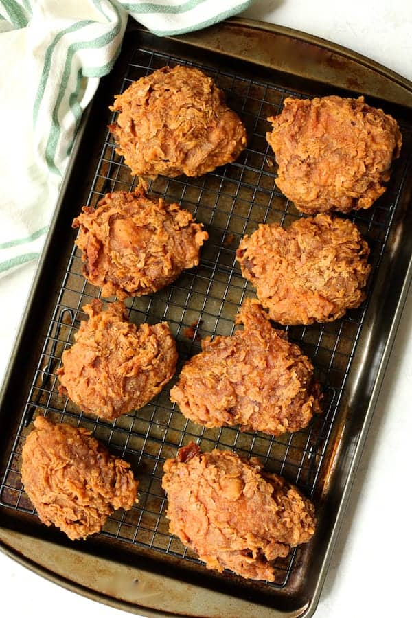 Photo of fried chicken on rack draining after being fried.