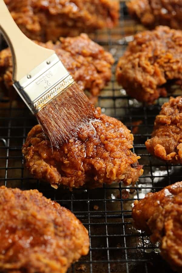 Photo of Nashville Style Hot Fried Chicken on rack being brushed with hot sauce.