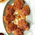 Nashville Style Hot Fried Chicken Hero Shot - Chicken on gray rimmed plate drizzled with hot sauce.