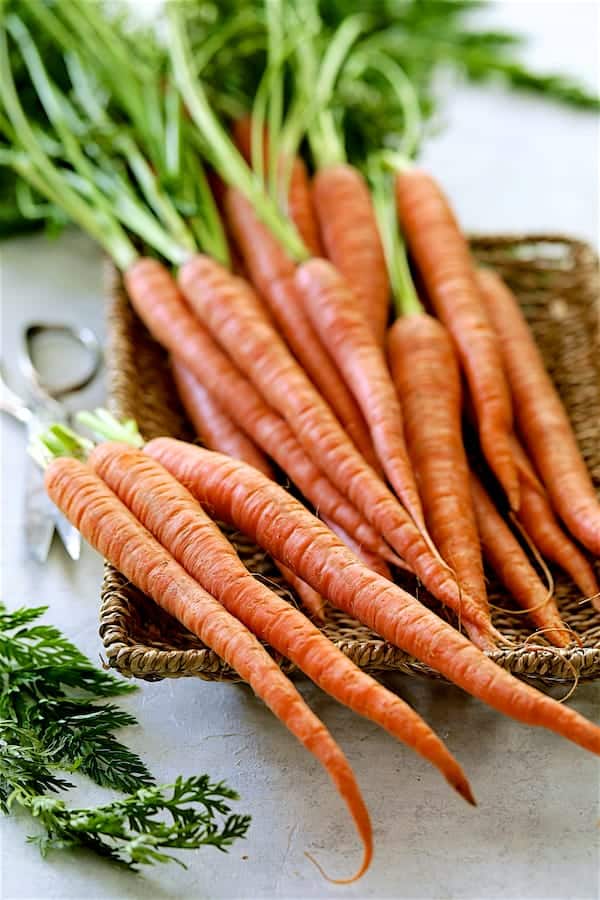 Photo of fresh carrots in wicker basket.