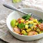 Seared scallops in white bowl with watermelon salsa on beige folded napkin.