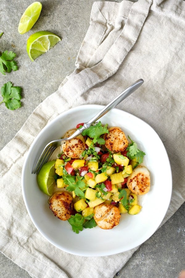 Photo of Seared Sea Scallops with Watermelon Tomato Salsa in white bowl garnished with cilantro and lime wedges.