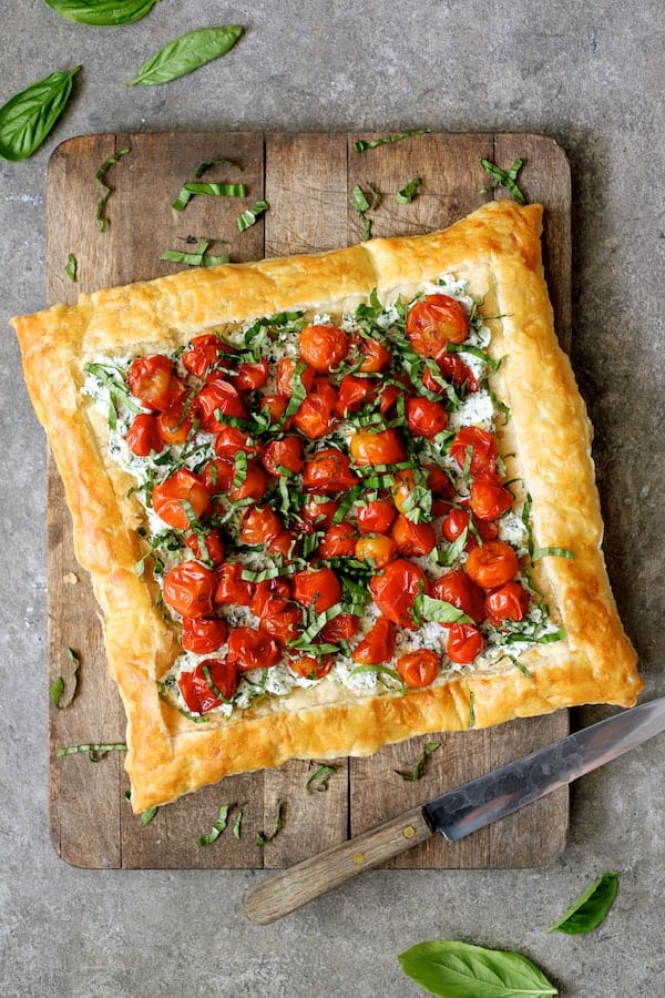 Photo of Roasted Cherry Tomato Tart with Herbed Ricotta on wood cutting board before being sliced.