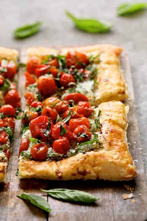 Photo of Roasted Cherry Tomato Tart with Herbed Ricotta on wood surface garnished with fresh basil.