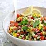 Middle Eastern Chopped Salad in a white serving bowl garnished with mint sprigs and lemon slices.