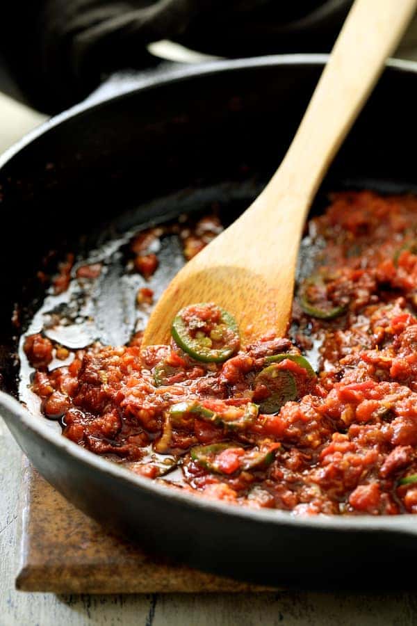 Photo of sauce for potatoes being stirred in cast iron skillet.