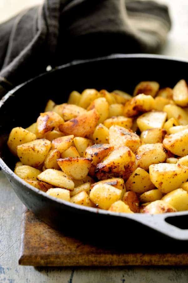Photos of browned potatoes in cast iron skillet.