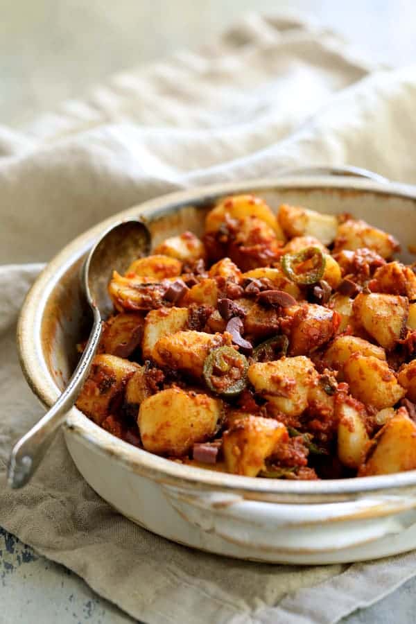 Photo of Patatas Bravas Chilenos in clay serving dish on beige towel.