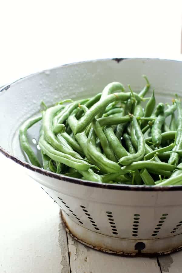 Photo of fresh uncooked green beans in white colander.
