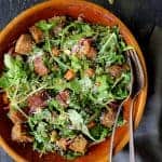 Autumn Panzanella Salad in wooden bowl with serving utensils.